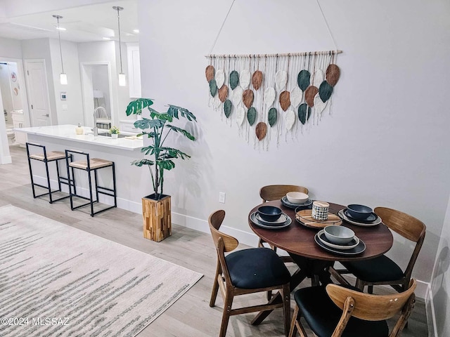 dining space with light hardwood / wood-style floors and sink