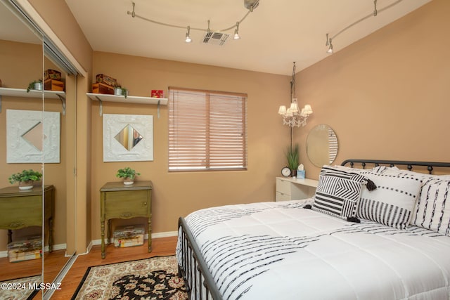 bedroom with a closet, hardwood / wood-style flooring, and an inviting chandelier