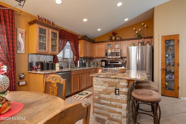 kitchen featuring appliances with stainless steel finishes, light stone countertops, a kitchen island, and light tile patterned floors