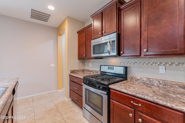 kitchen with light tile patterned flooring, light stone countertops, stainless steel appliances, and tasteful backsplash