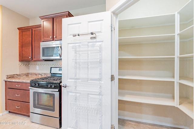 kitchen with backsplash, light tile patterned floors, and appliances with stainless steel finishes