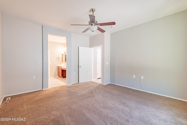 unfurnished bedroom with ceiling fan, light colored carpet, and ensuite bath