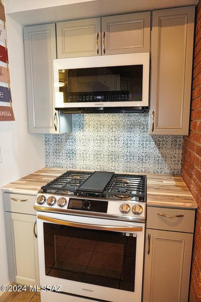 kitchen featuring stainless steel gas range, butcher block countertops, and decorative backsplash