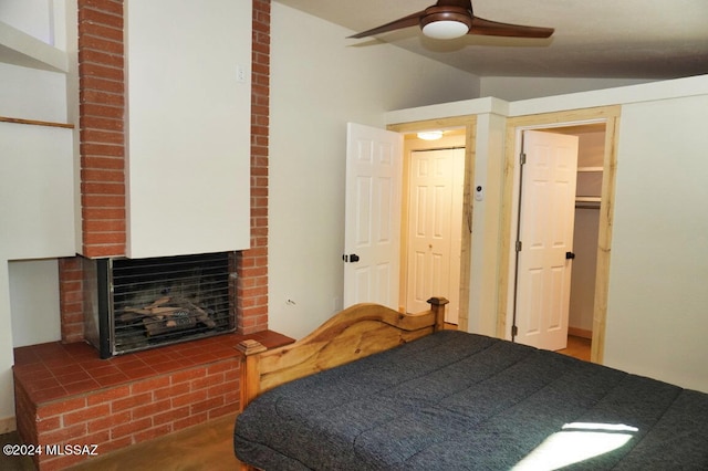 bedroom featuring vaulted ceiling, a brick fireplace, and ceiling fan