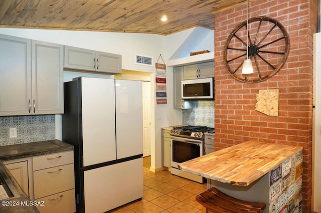 kitchen with vaulted ceiling, gray cabinetry, backsplash, light tile patterned floors, and white appliances