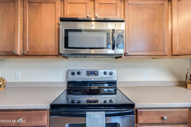 kitchen with light countertops, appliances with stainless steel finishes, and brown cabinetry