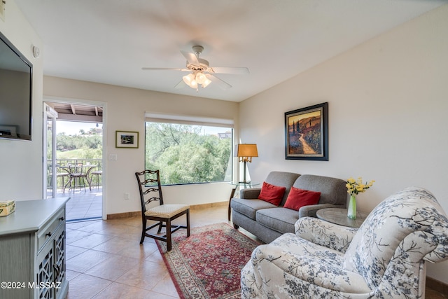 living area with light tile patterned floors, baseboards, and a ceiling fan