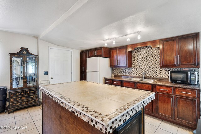 kitchen with tasteful backsplash, light tile patterned flooring, sink, and white refrigerator