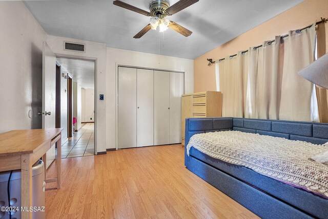 bedroom featuring light wood-type flooring, ceiling fan, and a closet