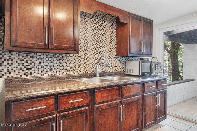 kitchen featuring decorative backsplash, sink, and light tile patterned floors