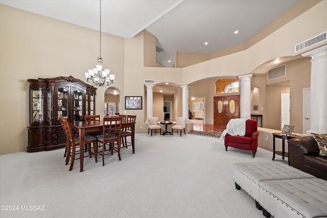 carpeted dining area featuring a notable chandelier, ornate columns, and high vaulted ceiling