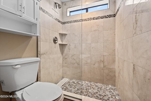 bathroom featuring a tile shower and toilet