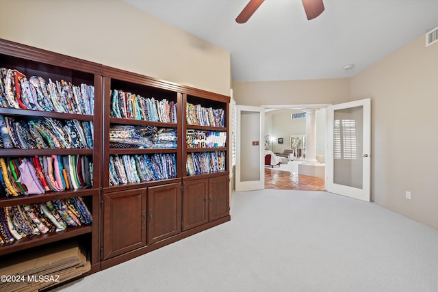 living area with light carpet, decorative columns, and ceiling fan