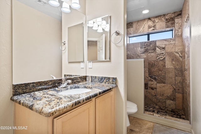 bathroom featuring tiled shower, vanity, and toilet