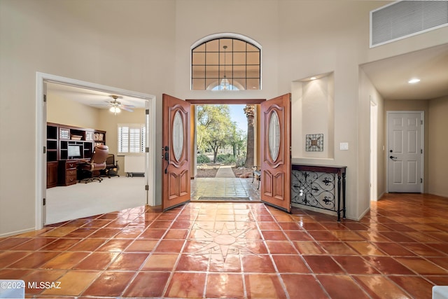 entryway with a high ceiling, ceiling fan, and tile patterned floors