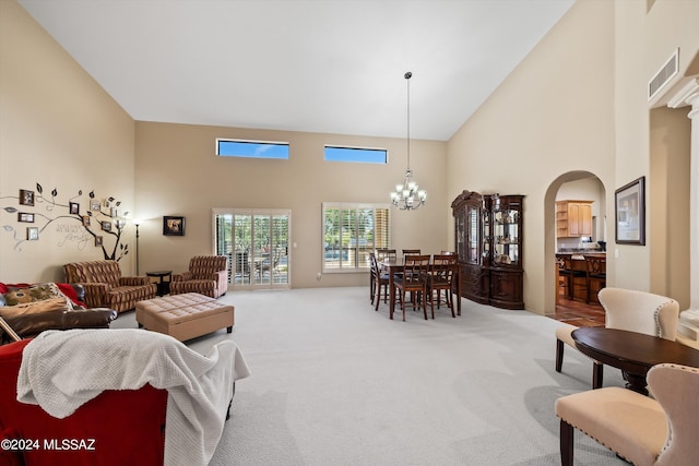 carpeted living room featuring high vaulted ceiling and a chandelier