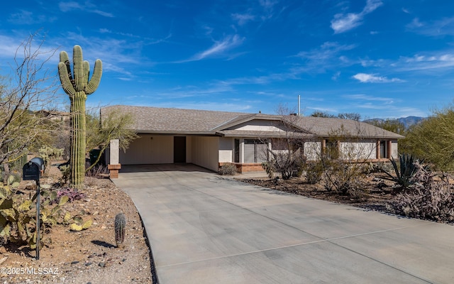 ranch-style home featuring brick siding, driveway, and a shingled roof