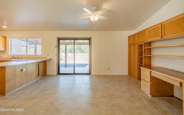 unfurnished living room featuring lofted ceiling, a sink, light tile patterned flooring, baseboards, and ceiling fan