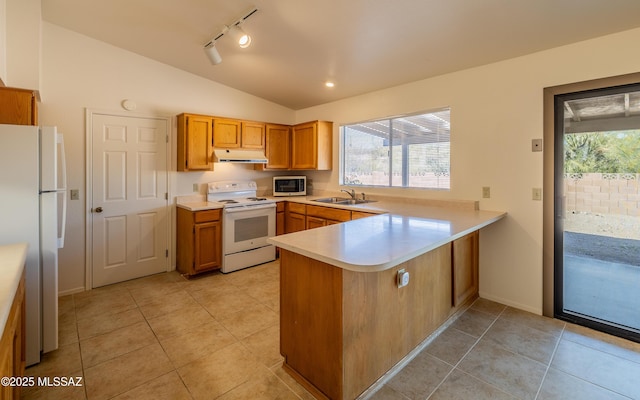 kitchen with white appliances, lofted ceiling, a peninsula, a sink, and under cabinet range hood