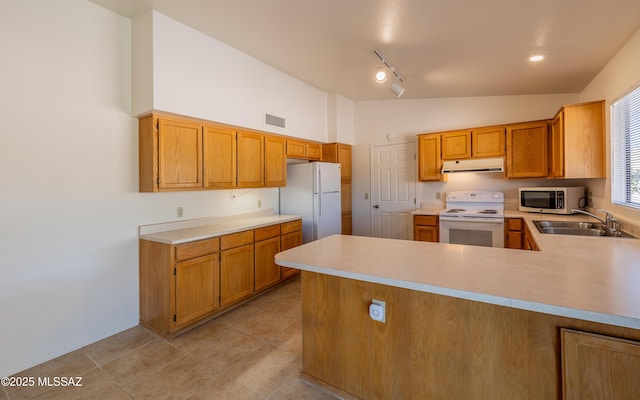 kitchen featuring visible vents, a sink, under cabinet range hood, white appliances, and light countertops