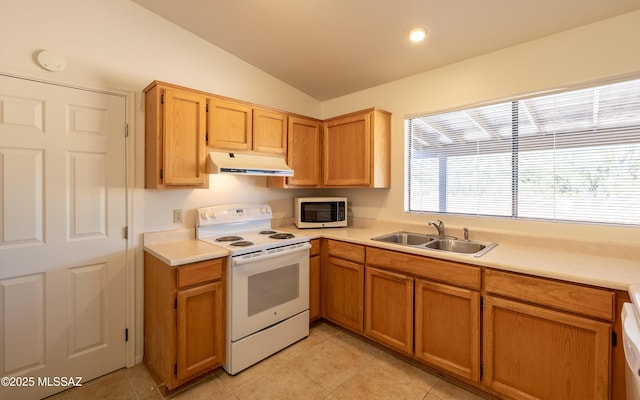 kitchen featuring under cabinet range hood, light countertops, vaulted ceiling, white appliances, and a sink