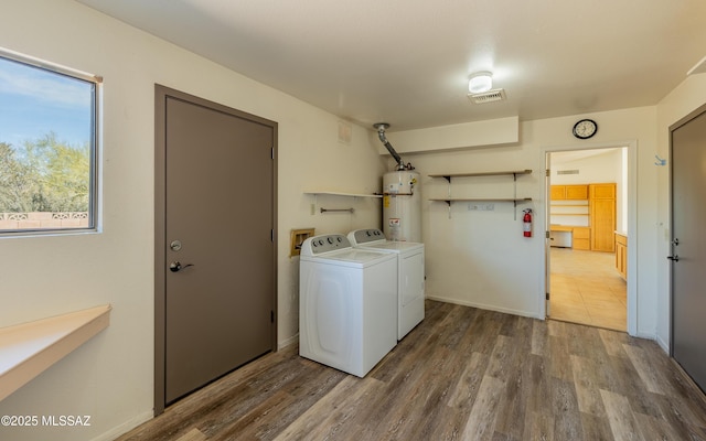 laundry room with washer and dryer, wood finished floors, visible vents, and water heater