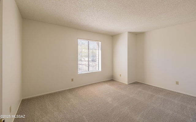 empty room with carpet flooring, a textured ceiling, and baseboards