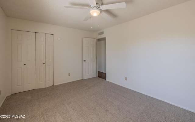 unfurnished bedroom with visible vents, carpet, a closet, and a textured ceiling