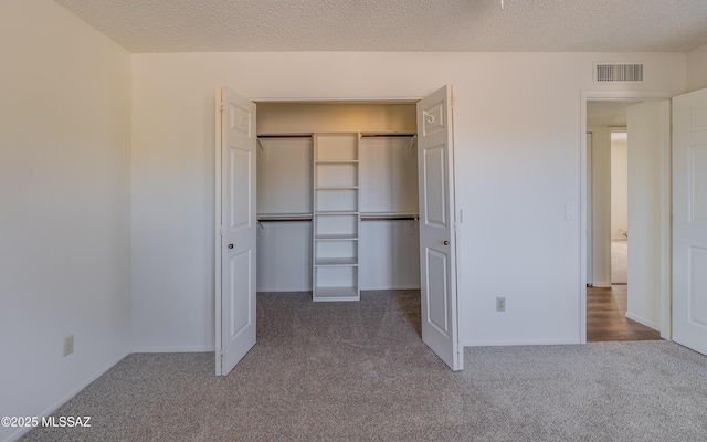 unfurnished bedroom with visible vents, carpet, a closet, and a textured ceiling