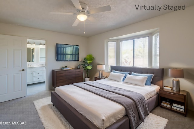 carpeted bedroom with a ceiling fan, ensuite bathroom, and a textured ceiling