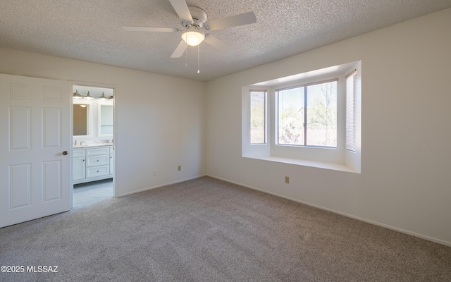 unfurnished bedroom with baseboards, carpet floors, a textured ceiling, and ensuite bath