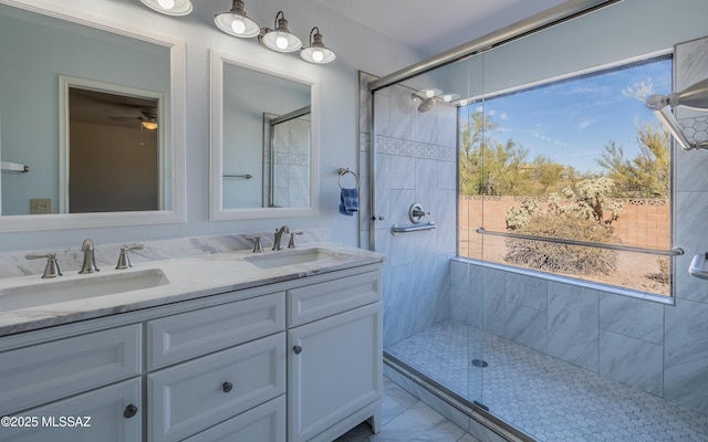 full bath featuring a sink, marble finish floor, double vanity, and a tile shower