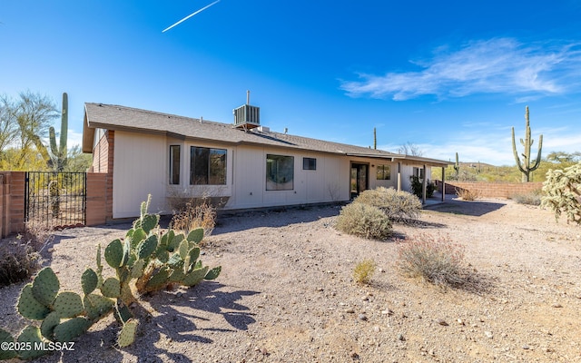 rear view of house featuring central AC unit and fence