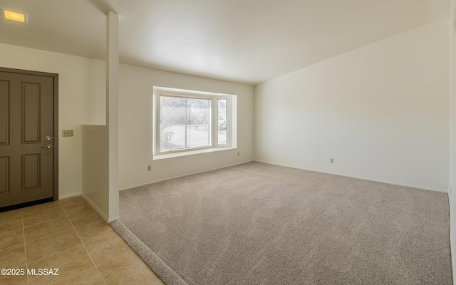 spare room featuring light tile patterned floors, light colored carpet, and baseboards