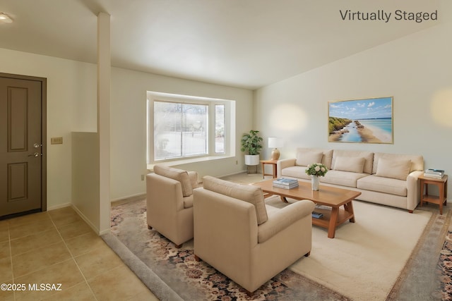 living area with vaulted ceiling, light tile patterned flooring, and baseboards