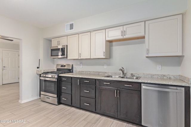 kitchen featuring white cabinets, stainless steel appliances, light stone countertops, and sink