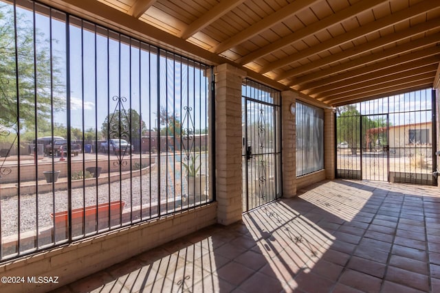 unfurnished sunroom with lofted ceiling with beams, a wealth of natural light, and wooden ceiling