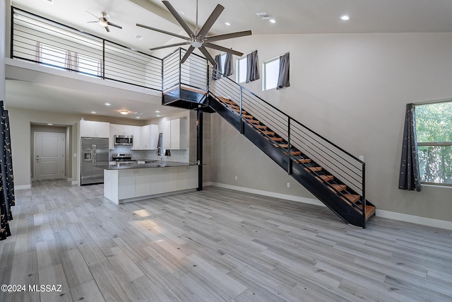 unfurnished living room featuring ceiling fan, light hardwood / wood-style floors, and high vaulted ceiling