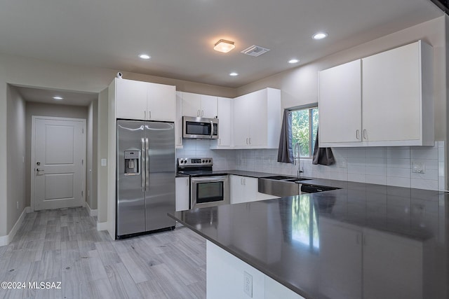 kitchen with white cabinetry, sink, decorative backsplash, appliances with stainless steel finishes, and light wood-type flooring