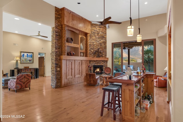 bar with ceiling fan, decorative light fixtures, light wood-type flooring, built in features, and a fireplace