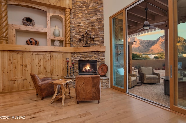 sitting room with ceiling fan, a fireplace, and wood-type flooring