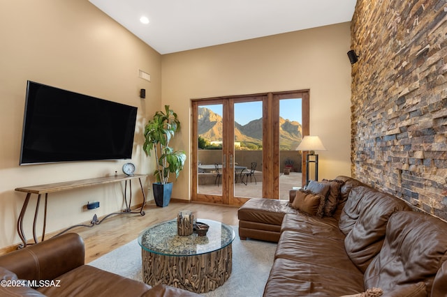 living room featuring high vaulted ceiling, french doors, and light hardwood / wood-style flooring