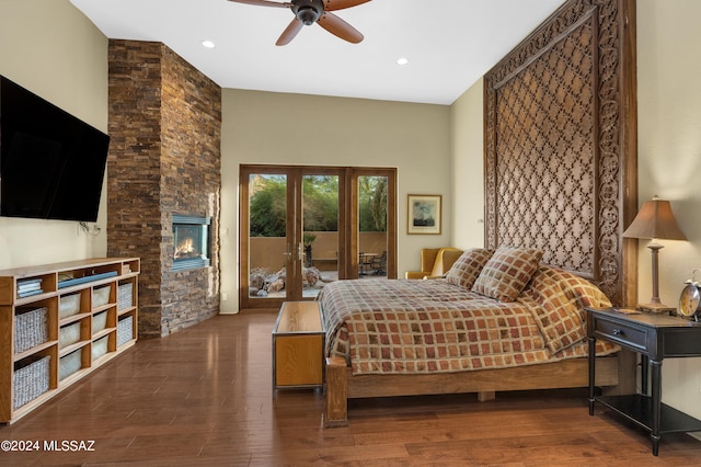 bedroom featuring dark wood-type flooring, french doors, a stone fireplace, access to outside, and ceiling fan