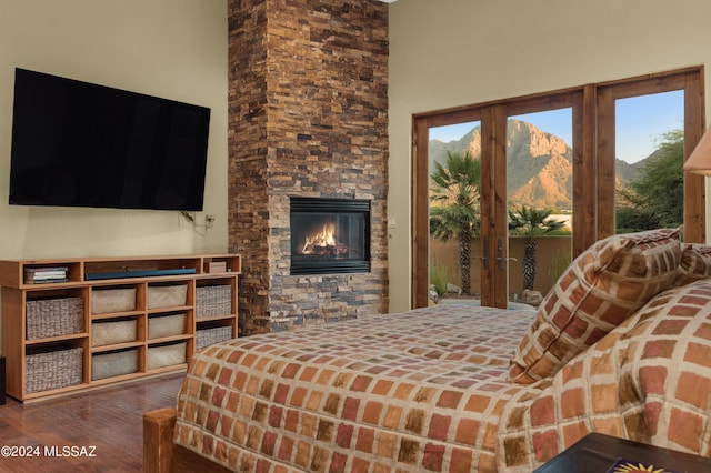 bedroom with a towering ceiling, a fireplace, hardwood / wood-style flooring, access to outside, and a mountain view