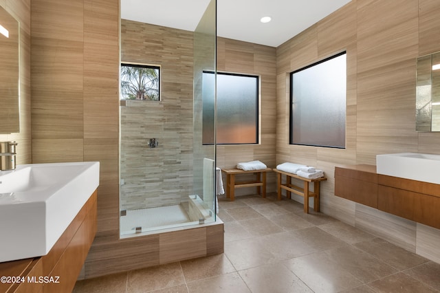 bathroom with tile patterned floors, tile walls, a shower with shower door, and vanity