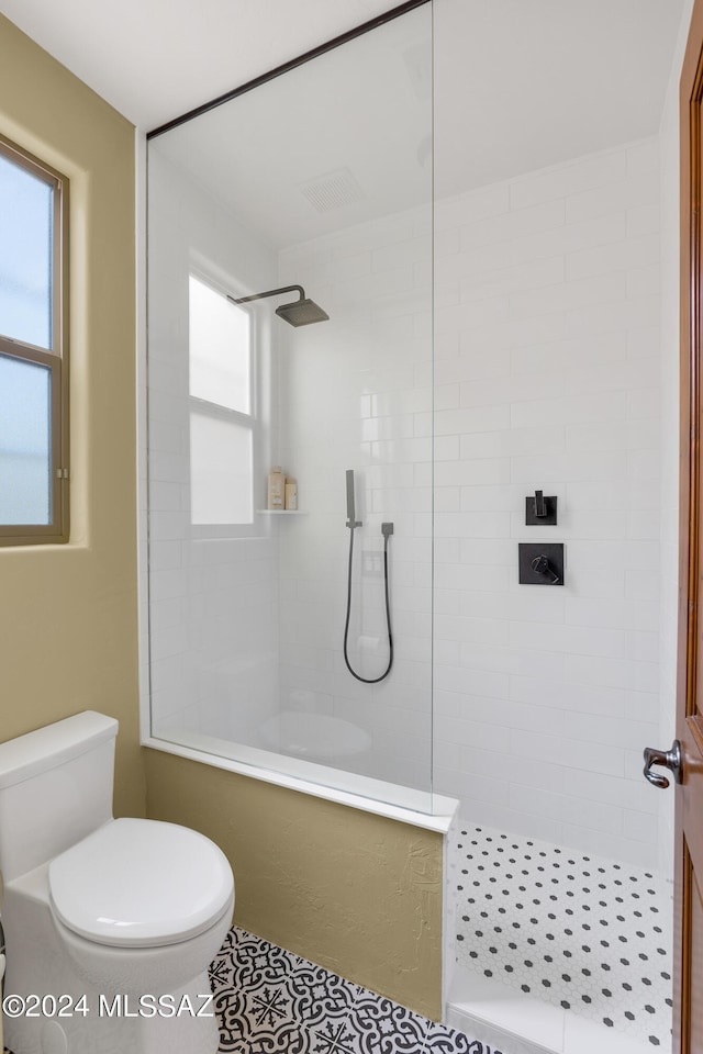 bathroom featuring toilet, a tile shower, and tile patterned floors