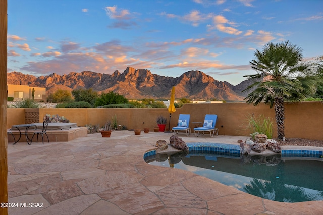 pool at dusk with a mountain view and a patio