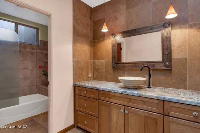 bathroom featuring tiled shower / bath combo, decorative backsplash, and vanity