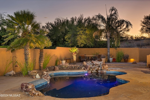 pool at dusk featuring a patio