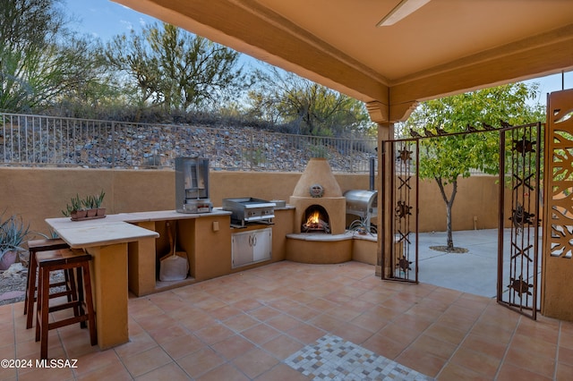 view of patio featuring exterior fireplace, a bar, and area for grilling